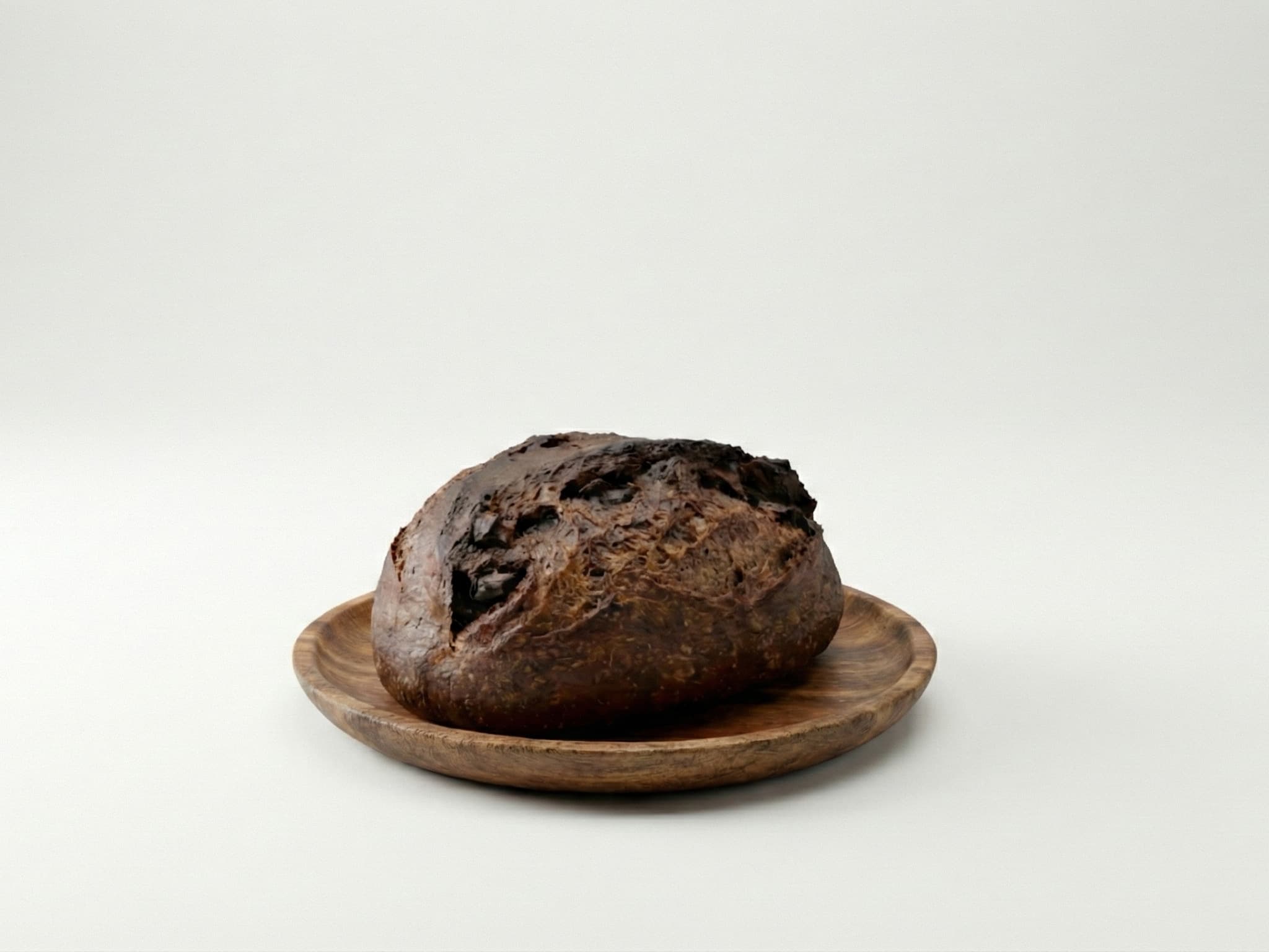 A chocolate sourdough loaf on a wooden plate