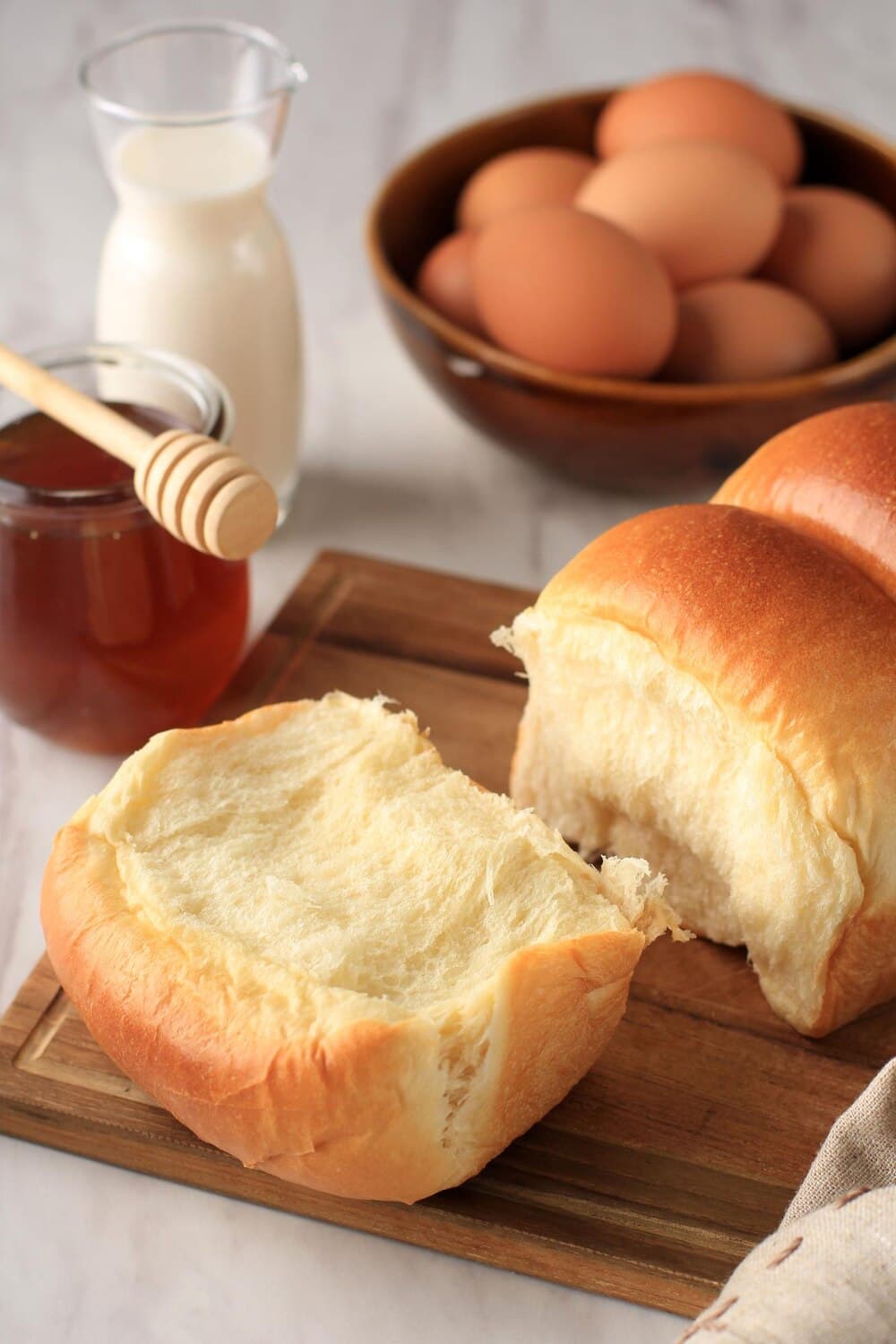 A Hokkaido milk bread torn open on a wooden board