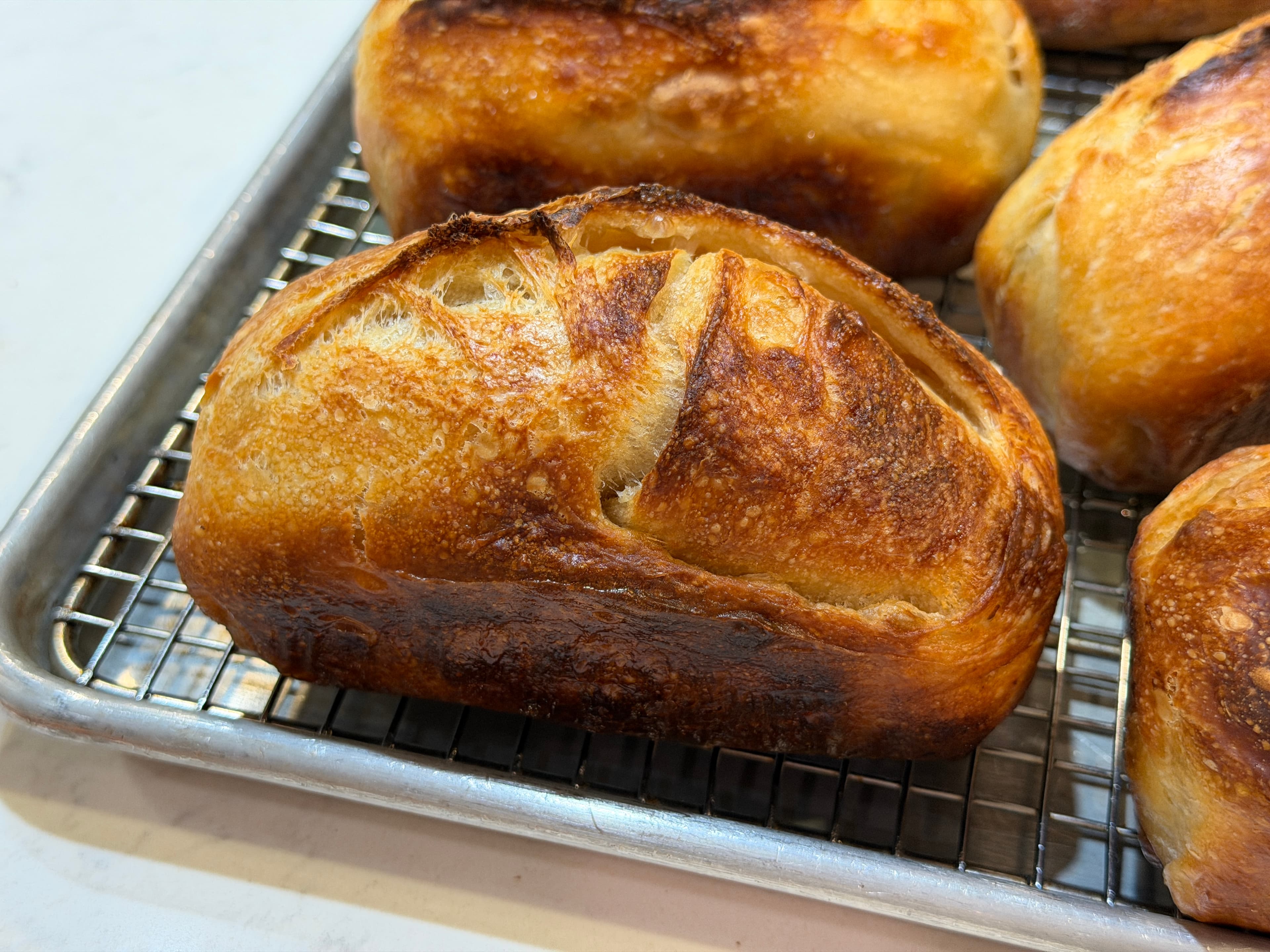 Golden sourdough mini batards on a cooling rack